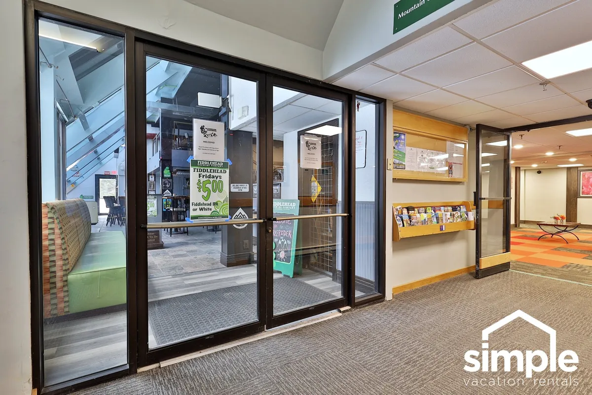 The main entrance and reception area of the property, with inviting doors, a comfortable seating area, and an informative wall display. The scene suggests a welcoming environment for arrivals and orientation, blending community and convenience.
