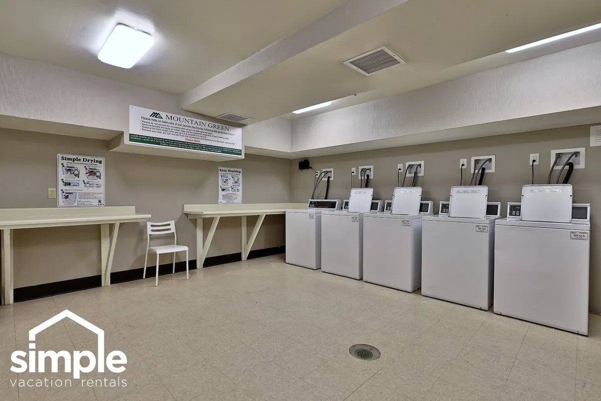 A practical image of the community laundry room, showcasing washing machines, a drying area, and informational posters. The scene suggests convenience for longer stays and the community aspect of shared amenities.