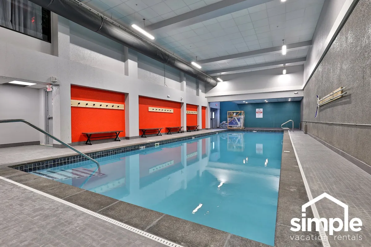 A bright, inviting indoor swimming pool area with benches along the poolside and vibrant walls, providing a glimpse into the resort's luxury amenities for post-ski relaxation.